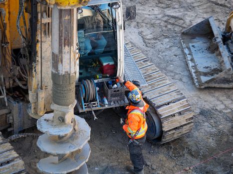 Services A construction worker in high-visibility gear operates heavy drilling equipment on a construction site.