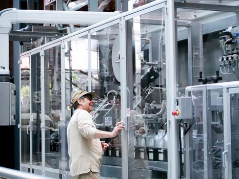Home Man observes and operates advanced industrial machinery behind glass indoors.