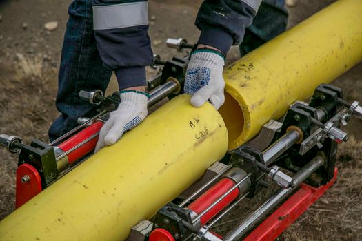 Services Close-up view of a worker using equipment to install yellow pipes outdoors, focusing on hands and tools.